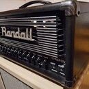 Černý kytarový zesilovač s kovovou mřížkou na předním panelu. Na mřížce je umístěno stříbrné logo Randall a vpravo dole nápis THRASHER. Ovládací pane…