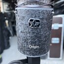 Detailní pohled na mikrofon s černým, strukturovaným povrchem připomínajícím kůži nebo kámen. Uprostřed je umístěno plastové logo ve tvaru stylizovan…