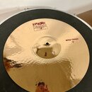 Zlatý kovový činel s kladeným povrchem. Na povrchu jsou červené nápisy „Paiste 2002“, „TRADE MARK MADE IN SWITZERLAND“ a „WILD CRASH 19"“. Povrch je…