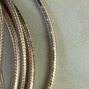 Detailní záběr na svinutý kabel s kovovým pleteným povrchem v stříbrné barvě. Na povrchu kabelu je černý nápis VAN DAMME SILVER SERIES SESSION GRADE.…