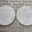 Dvě bílé bicí blány s kovovými obručemi položené na dlažbě. Obě blány mají v horní nebo dolní části logo REMO. Povrchy blan vykazují známky opotřeben…