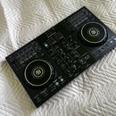 Černý DJ kontrolér s dvěma jog-koly a centrálním mixážním sekcí. Na horní části je bílé logo Pioneer DJ a v pravé části nápis DDJ-400. Povrch přístro…