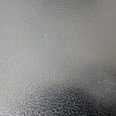 Fotografie detailně zachycuje povrch černého materiálu s texturou imitující kůži. Povrch je v dobrém stavu, bez viditelných značek, log nebo nápisů.