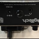 Černý plastový přístroj s nápisem DigiTech. Na spodní straně jsou vidět konektory pro napájení s označením 9VDC 800mA a výstup VOLUME. V levém rohu j…