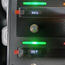Detailní pohled na černý ovládací panel s kovovými přepínači. Na panelu jsou viditelné bílé nápisy RIG s šipkou nahoru, AMP a RIG s šipkou dolů a DOU…