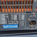 Detail zadní strany černého elektronického zařízení, pravděpodobně zesilovače. Na bílém štítku je uveden nápis VPL - VOLTAGE PEAK LIMITER s tabulkou…