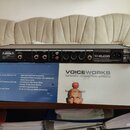 Černý rackový procesor TC-HELICON VoiceWorks. Na zadním panelu jsou viditelné vstupy a výstupy, včetně konektorů XLR a jack, s popisky jako MIC IN, L…