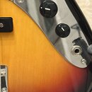Detail elektrické kytary s tělem v barevném přechodu od žluté přes oranžovou k červené a černé. Nástroj má chromovaný plech s třemi černými oválnými…