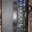 Černý kytarový kombozesilovač s ovládacím panelem. Na panelu je nápis DNAfx Amp10 a řada ovládacích prvků s popisky GUITAR, MODULATION, PREGAIN, DRIV…