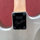Detail zadní strany krku a těla elektrické kytary v stříbrné barvě. Na černém plastovém krytu spojení krku s tělem je bílý nápis JFFG21000049, pod ní…
