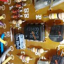Detailní pohled na elektronickou desku s osazenými součástkami. Uprostřed je umístěn integrovaný obvod s nápisy 4558DD, JRC a 00 8B. Kolem jsou vidět…
