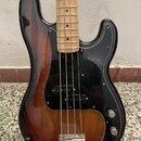 Elektrická basová kytara s korpusem v červenohnědém sunburst provedení a černým pickguardem. Hmatník je vyroben ze světlého dřeva s černými tečkovými…