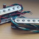 Dva elektrické snímače typu single-coil s kovovými kryty a šesti viditelnými polosférickými póly. Snímače mají připojovací vodiče v červené, zelené a…