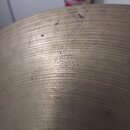 Detail povrchu kovového činele s viditelným broušením. Uprostřed je vyražen nápis v arabském písmu a pod ním text AVEDIS ZILDJIAN CO GENUINE TURKISH…