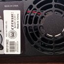 Detail zadní strany černého elektronického zařízení s ventilátorem a konektory. Na bílém štítku je uveden nápis CROWN, ELKHART, INV4517, Made in Chin…