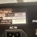 Detail štítku na zadní straně černého přístroje. Na štítku je logo a nápis Roland, dále údaje AC 230 V~50/60Hz 43W, MODEL JC-40 a SERIAL NO. Z2G2876…