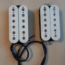 Dvě elektrické kytarové snímače typu humbucker s bílými plastovými kryty. Na obou je z levé strany svisle napsán nápis Seymour Duncan. Snímače mají č…