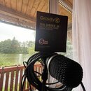 Na fotografii je černý držák na nápoje v originálním kartonovém obalu, který stojí na mikrofonu. Na obalu je žluté logo Gravity a nápisy MA DRINK M,…