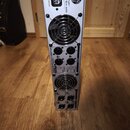 Stříbrný výkonový zesilovač v rackovém provedení. Na horním panelu je nápis behringer a MODEL NU4-6000. Zařízení obsahuje dva velké ventilátory, něko…