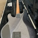 Zadní strana elektrické kytary s trpyřivým stříbrným povrchem v černém tvrdém kufru. Nadesníkovádeska nese nápis "MADE IN USA" a sériové číslo "18147…