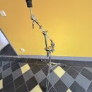 Kovový mikrofonní stojan s černou základnou a černým držákem na mikrofon v horní části. Stojan je vybaven několika klouby a utahovacími šrouby pro na…