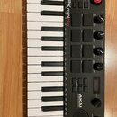 Černý kompaktní MIDI kontrolér s červeným rámem. Na horní části je nápis MPK mini play a v dolní části logo AKAI PROFESSIONAL. Nástroj obsahuje kláve…