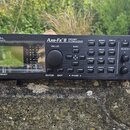 Černý rackový procesor s nápisy FRACTAL AUDIO SYSTEMS a Axe-Fx II PREAMP & FX PROCESSOR. Zařízení má vlevo displej s nápisem G2 MODELING TECHNOLOGY,…