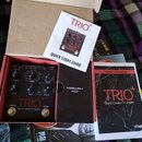 V kartonové krabici se nachází černý efekt pedál s nápisy TRIO+ a Band Creator + Looper. K zařízení patří Quick Start Guide, Owner's Manual s nápisem…