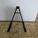 Černý skládací stojan z kovových trubek s plastovými zakončeními. Stojan má tvar písmene A a v horní části je opatřen plastovou opěrnou hlavou. Na po…