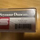 Fotografie znázorňuje krabičku s hudebním příslušenstvím. Na bílém štítku je uveden nápis Seymour Duncan®, označení SH-4, JB Model White a kód 11102-…