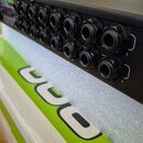 Černý rackový přístroj s řadou konektorů XLR na zadní straně. Na levém horním rohu je viditelné zelené logo, z něhož je čitelné slovo "PRO". Přístroj…