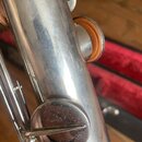 Detailní záběr na stříbrný kovový trubičný nástroj s mechanikou a polštářky. Povrch kovu vykazuje viditelné opotřebení, množství drobných škrábanců a…