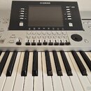 Stříbrošedý digitální klavír s černým ovládacím panelem a displejem. V horní části panelu je bílé logo YAMAHA. Pod displejem se nachází řada tlačítek…
