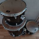 Tři černé bubny s kovovými obručemi a ladidly. Na dvou z nich je vidět logo CB drums, na prostředním bubnu je dále nápis UN a nečitelný text pod ním.…