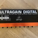 Zadní strana audio rozhraní v černé barvě s oranžovým spodním panelem. Na zařízení je velký bílý nápis ULTRAGAIN DIGITAL a pod ním text AUDIOPHILE 8…