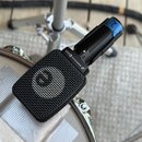 Černý dynamický mikrofon s mřížkou, umístěný na bílém bubnu. Na těle mikrofonu je bílý nápis SENNHEISER e906 a logo značky. Na horní části těla je mo…