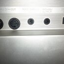 Detail stříbrného zadního panelu elektronického nástroje s řadou konektorů. Nad vstupy jsou nápisy IN — MIDI — OUT, FOOT SWITCH, PHONES/ OUTPUT a DC…
