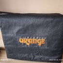 Černý textilní přepravní obal nebo brašna. Uprostřed je našitý nášivák s oranžovým nápisem ORANGE. Povrch materiálu vykazuje opotřebení v podobě drob…