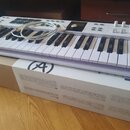 Bílá MIDI klaviatura s černými klávesami, položená na originální krabici. Na horním panelu je nápis ARTURIA a řada ovládacích prvků, včetně bílých kn…