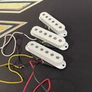 Tři elektrické snímače typu single-coil v bílém provedení. Každý snímač má šest viditelných kovových pólů a montážní otvory na okrajích. Z každého sn…