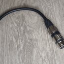 Černý kabel s konektory na obou koncích. Na levé straně je pozlacený 6,3mm jack konektor s vrubeným kovovým prstencem. Na pravé straně je stříbrný XL…