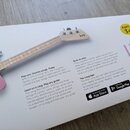 Fotografie znázorňuje krabici s dětskou elektrickou kytarou v růžové barvě s bílým trupem a světle hnědým hmatníkem. Na hlavě nástroje je viditelné l…