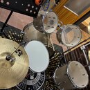 Kytice bubenů v šampaňské barvě s kovovým kováním a bílým membránou snare bubnu. Na činelech je vidět nápis Zildjian, označení 14" HI-HAT Top a logo…