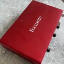 Červené kovové audio rozhraní s nápisem Focusrite na horním krytu. Na pravém boku jsou vidět čtyři černé ovládací knoflíky a jeden stříbrný konektor.…