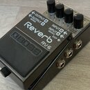 Kytarový efekt pedál v šedém kovovém provedení s černým spínacím pedálem. Na horní části je bílý nápis Reverb a model RV-6, v levé části je vyražené…