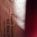 Detail vnitřní štítky smyčcového nástroje z papíru. Na štítku je černý tisk s textem „Copy of Joseph Guarnerius del Gesù 1741“ a nápisem „Made in Wes…