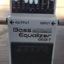 Šedý kytarový pedál s nápisy Bass Equalizer a GEB-7. V horní části jsou bílé posuvníky s označením frekvencí 50, 120, 400, 500, 800, 4.5k, 10k a Leve…