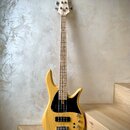 Elektrická basová kytara s přírodním dřevěným povrchem těla a hmatníkem. Na hlavě je viditelné logo ve tvaru motýla. Instrument má černý pickguard, č…