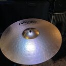 Stříbrný cymbál s koncentrickým žebrováním, umístěný na kovovém stojanu. Na povrchu je černý nápis PAiste 2008 bronze a pod ním text 18" CRASH RIDE.…