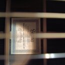 Fotografie zachycuje vnitřní štítek akustické kytary viditelný skrz otvor rezonanční desky. Na štítku je uveden nápis Sigma, Model = DR-28 a Serial #…
